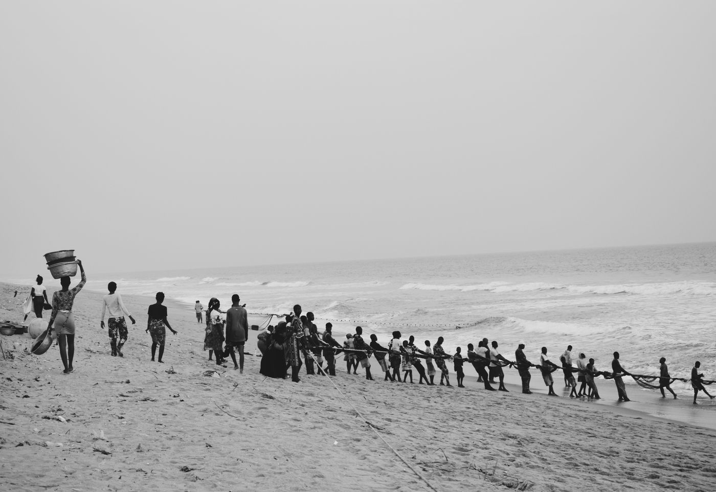 People pulling a fishing net together along Badagry Beach, Nigeria.